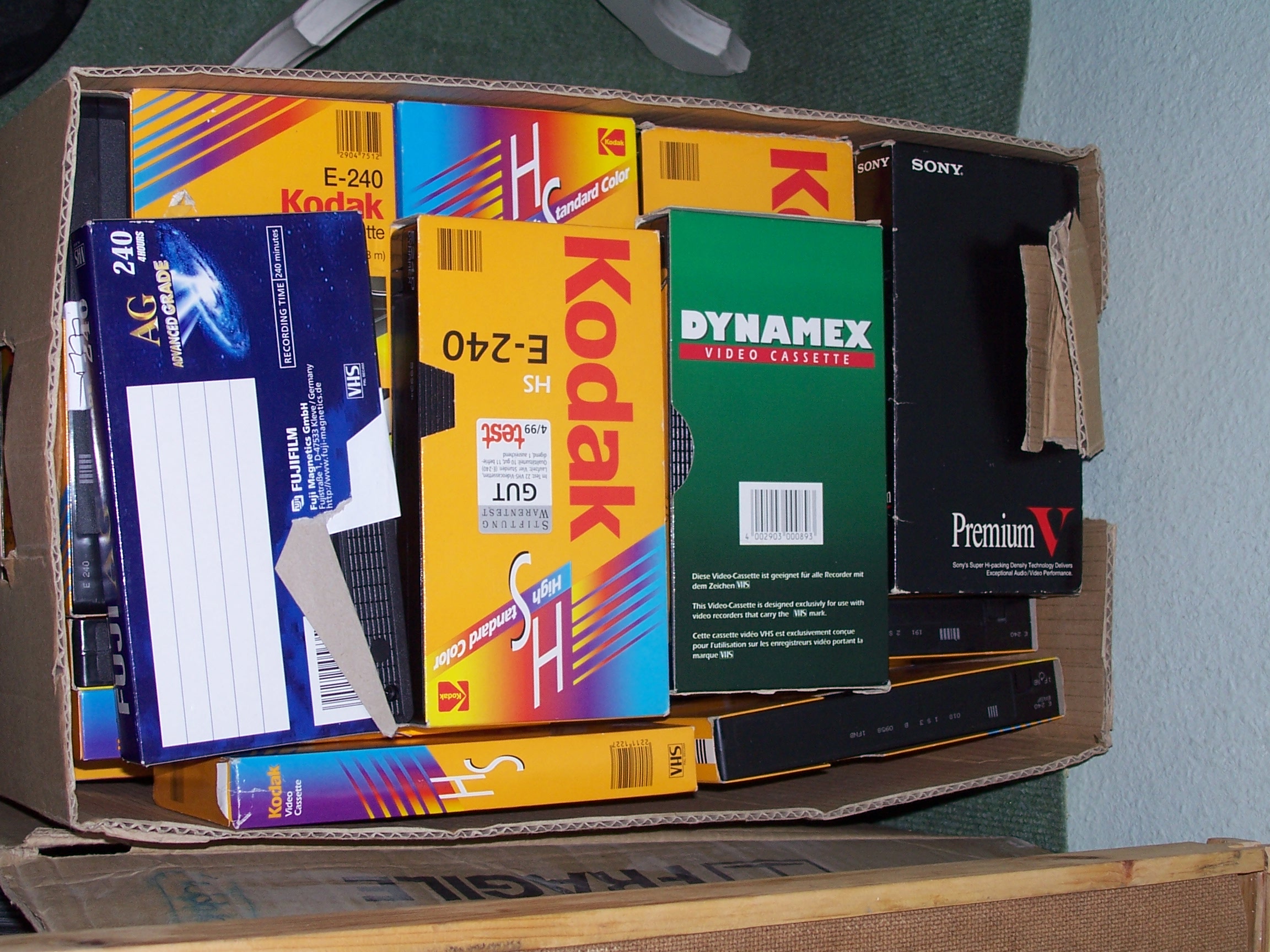 Ein Pappkarton, gefüllt mit gebrauchten VHS-Leerkassetten verschiedener Marken.