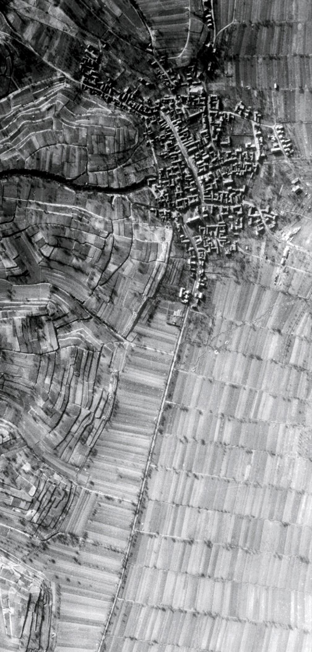 Luftbildaufnahme der US-Streitkräfte von Kippenheim (BW). Man sieht das Dorf und die Bundesstraße 3, die den Ort teilt. Östlich (links im Bild) sieht man die Terrassen der Vorbergzone, die weiter östlich in den Schwarzwald übergeht. Westlich ist die Rheinebene bzw. die Oberrheinische Tiefebene unter der der Oberrhein Aquifer ein riesiger Wasserspeicher liegt. Auf den Terrassen beginnt der Weinbau, in der sehr fruchtbaren Ebene wachsen Mais, Tabak und Getreide. Ein Tal mit Lößwänden aus Schluff ist am linken oberen Bildrand zu sehen.