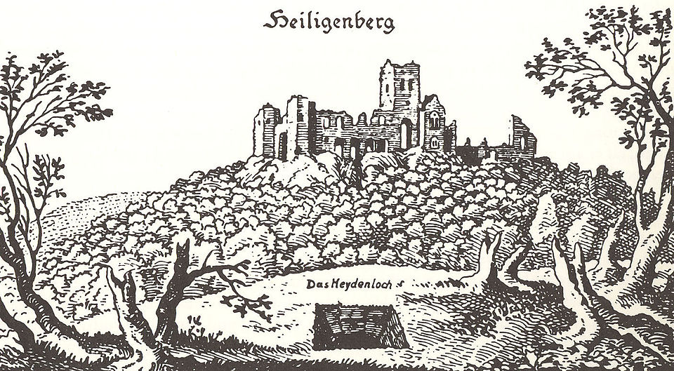 Holzschnitt eines bewaldeten Hügels mit einer Ruine auf der Kuppe, darüber seht "Heiligenberg". Im Vordergrund ein qudratisches Loch, das in die Tiefe führt. Es ist mit "Das Heydenloch" beschriftet. Die Bäume in seiner unmittelbaren Umgebung sind nur Stümpfe, die beiden etwas weiter entfernt, wirken ein wenig zerzaust.